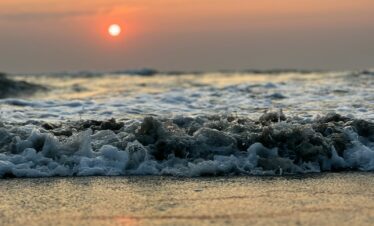 the sun is setting over the ocean waves